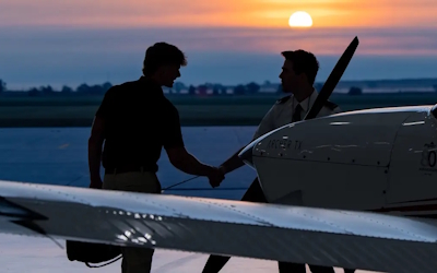 Students shaking hands behind airplane
